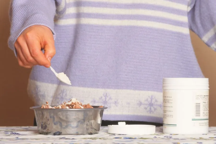 Person adding supplement powder to pet food